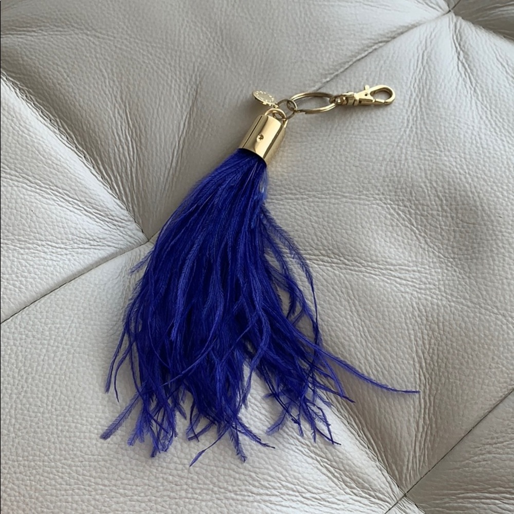 BCBG MaxAzria bag charm or keychain with a blue feather tassel and gold hardware